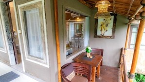 A wooden dining table with chairs, a hanging light fixture, and a framed picture on the wall. - Room-romantic Jungle Nest (Ubud)