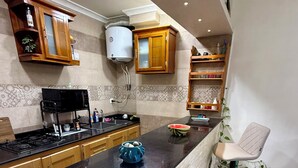 Uma cozinha moderna com armários de madeira, bancada preta, fogão embutido e um banco de balcão.