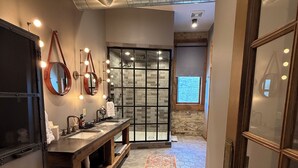 Een moderne badkamer met een wastafel, spiegels en een douche.