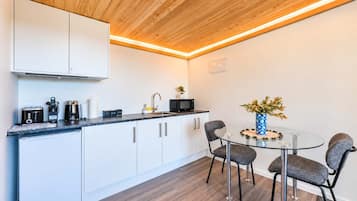 Een moderne keuken met witte kasten, een zwart aanrecht en een ronde glazen tafel met stoelen.