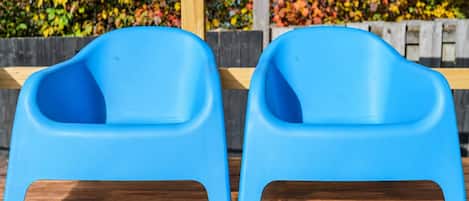 Two blue plastic chairs with a wooden bench in the background.
