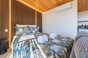 A bedroom with a bed, pillows, a bedside table, and a built-in air conditioning unit. - Skyline Haven | Lake Tekapo + Lake Views (Lake Tekapo)