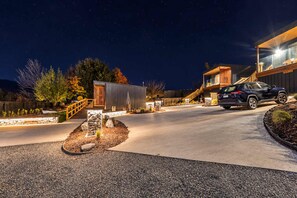 Ein modernes Wohnhaus mit Auffahrt, einer Holzterrasse und einem geparkten Fahrzeug auf der Auffahrt.