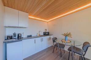 Una cocina moderna con armarios blancos, un microondas y una mesa de vidrio con sillas.