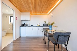 Eine moderne Küche mit weißen Schränken, einem Glastisch und einer Holzbalkendecke.