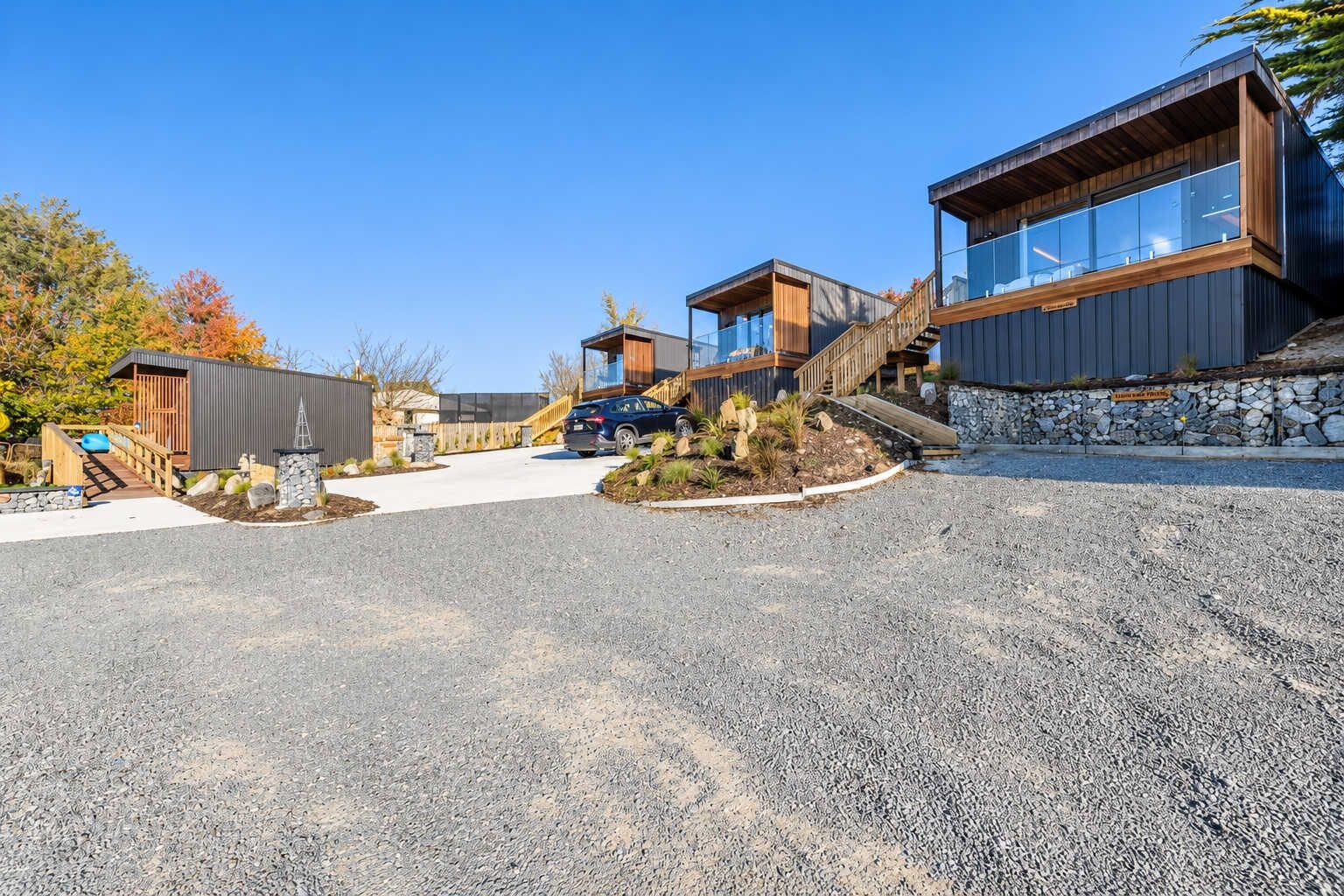 A modern building with a stone facade, a wooden deck, and a clear sky.