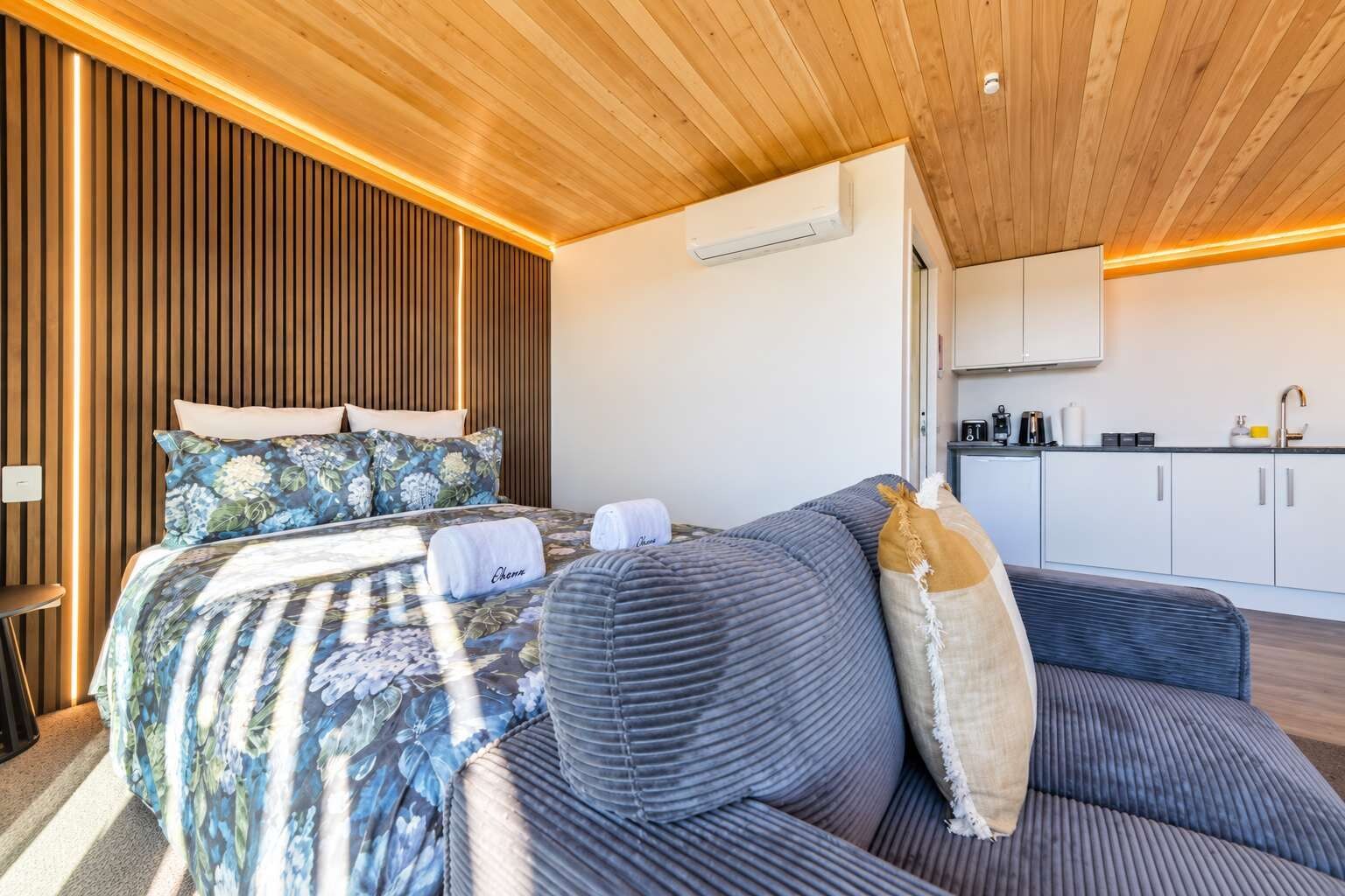 Een moderne kamer met een bed, een slaapbank en een kitchenette.
