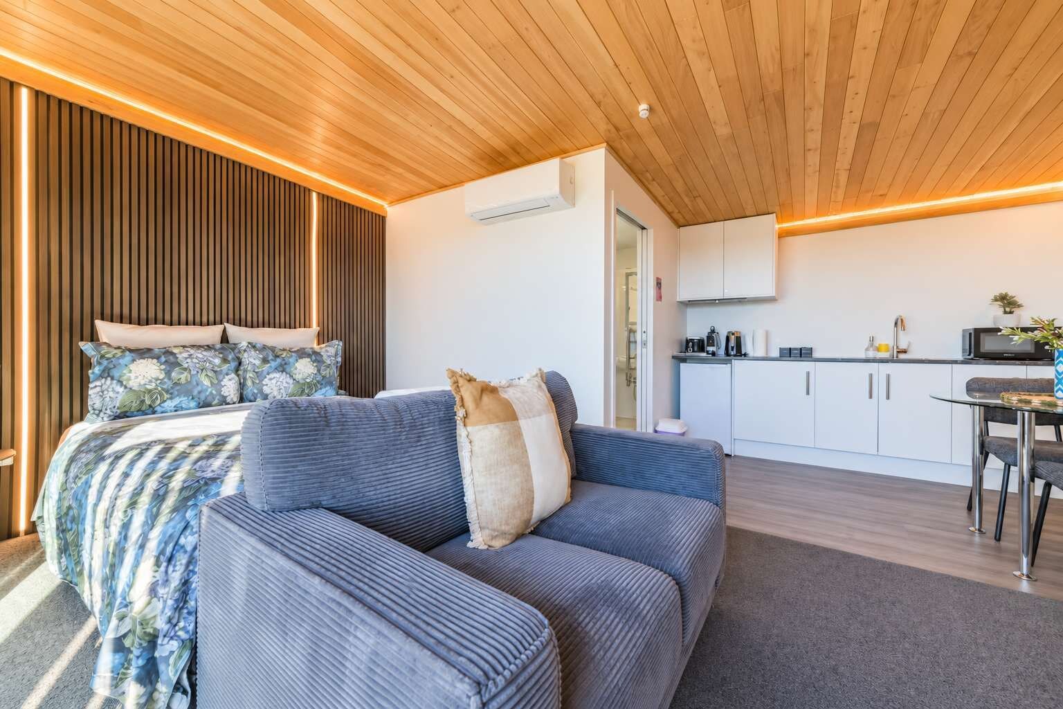 Een moderne slaapkamer met een bed, een slaapbank en een kitchenette.