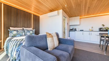 Een moderne slaapkamer met een bed, een slaapbank en een kitchenette.