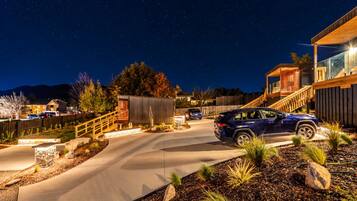 A residential driveway with a blue SUV parked, surrounded by landscaped gardens and a wooden fence.