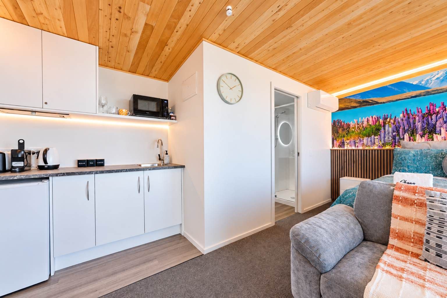 A modern kitchen with white cabinets, a microwave, and a coffee machine.