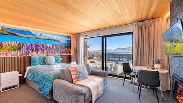 A hotel room with a bed, a sofa, a small table, and a TV.