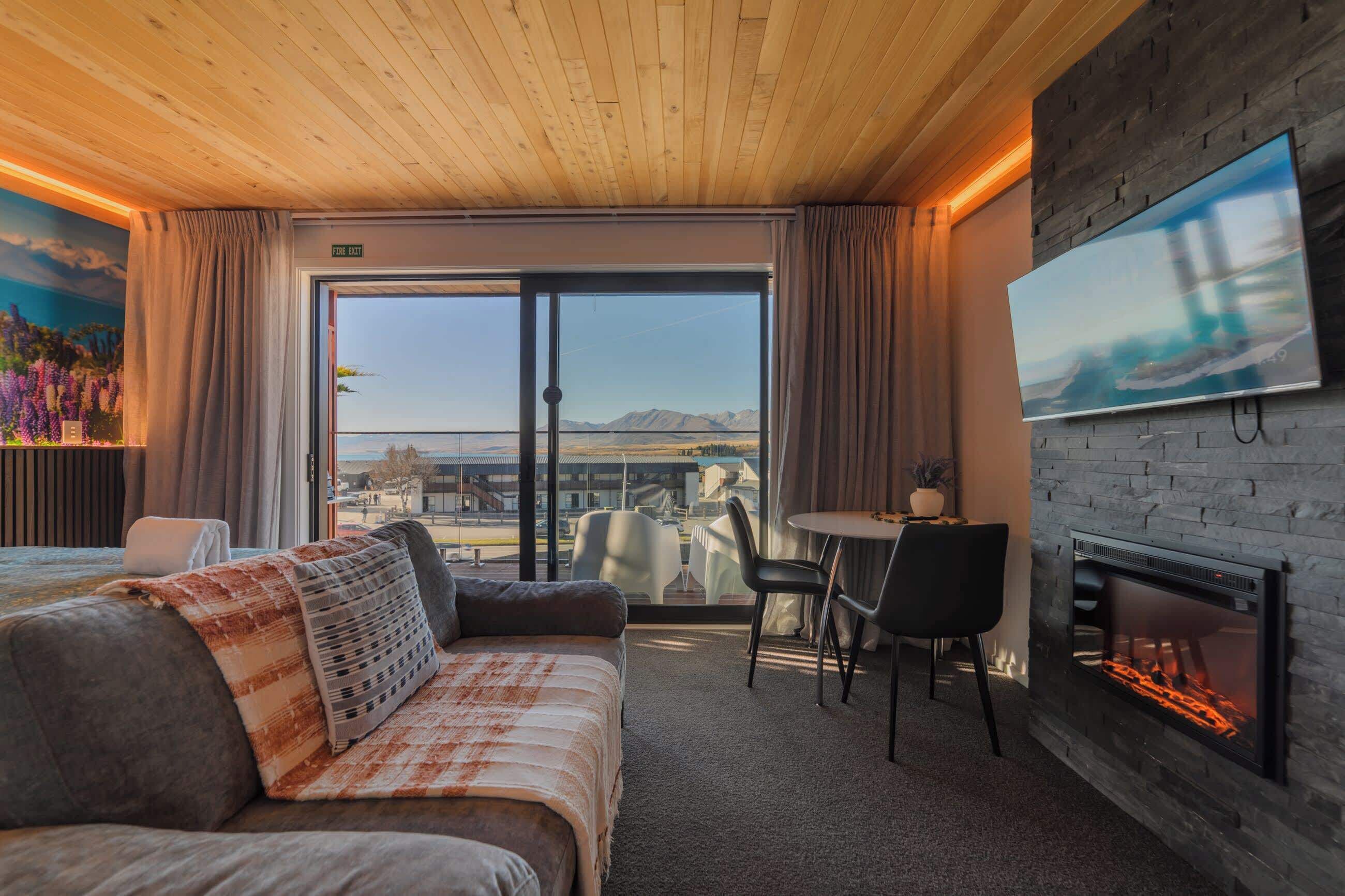 Ein Hotelzimmer mit Bett, Fernseher, Kamin und Blick ins Freie.