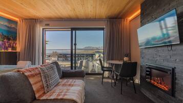 Ein Hotelzimmer mit Bett, Fernseher, Kamin und Blick ins Freie.