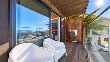 A balcony with a view of the city, a wooden ceiling, and a seating area with white chairs.