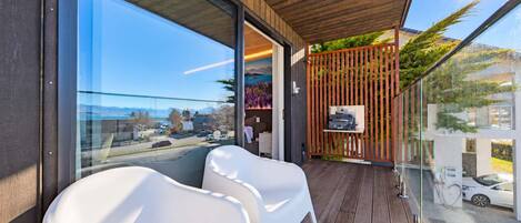 Een balkon met uitzicht op de stad, een houten plafond en een zithoek met witte stoelen.