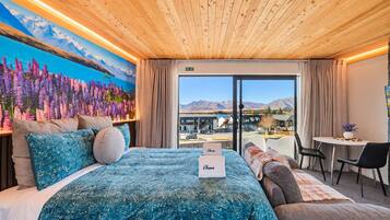 Una habitación de hotel con una cama, un escritorio y vistas a montañas.