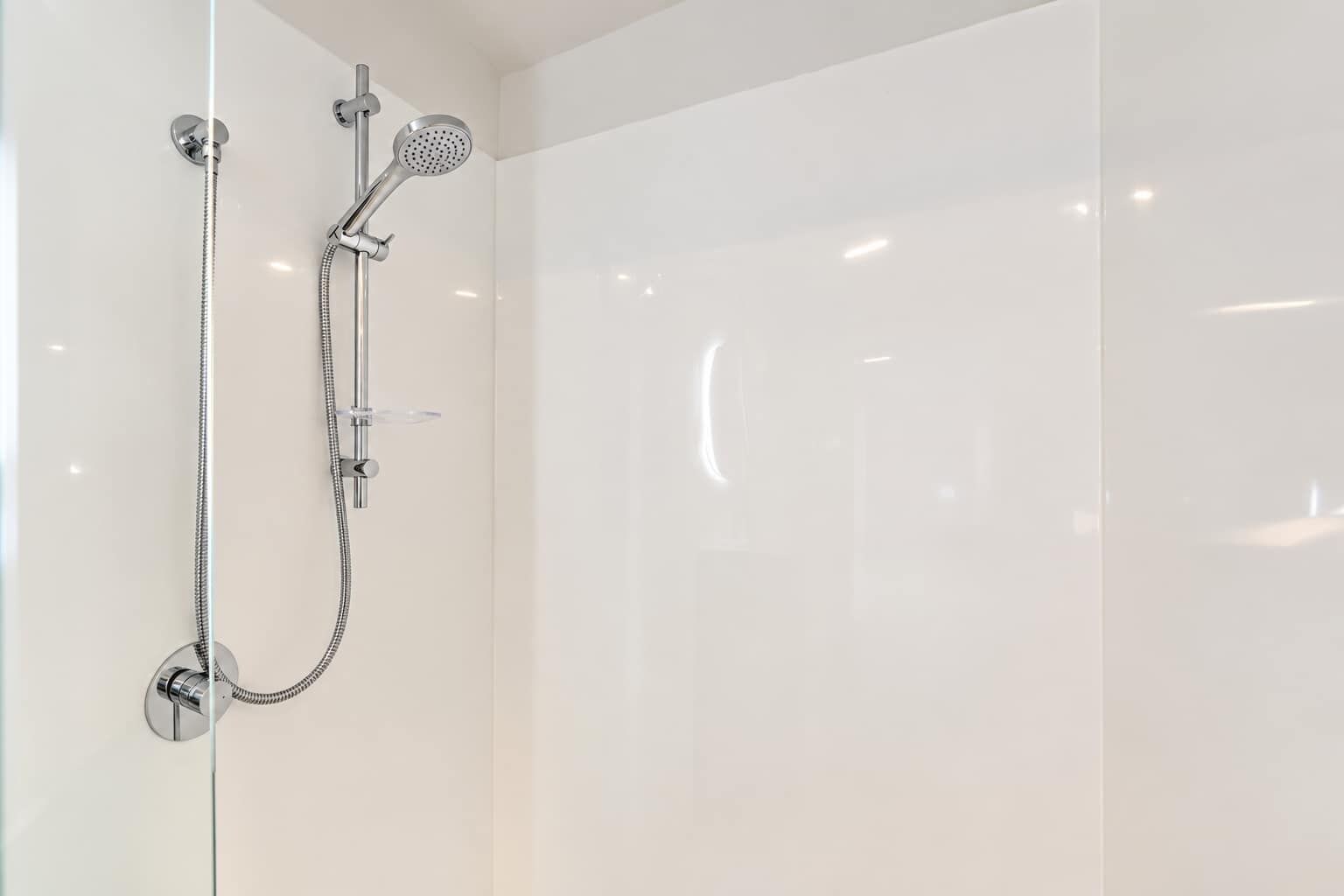 A modern shower with a handheld showerhead and a fixed wall-mounted showerhead.