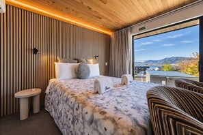Habitación de hotel con una cama, una mesita de noche, una silla y vistas al exterior.