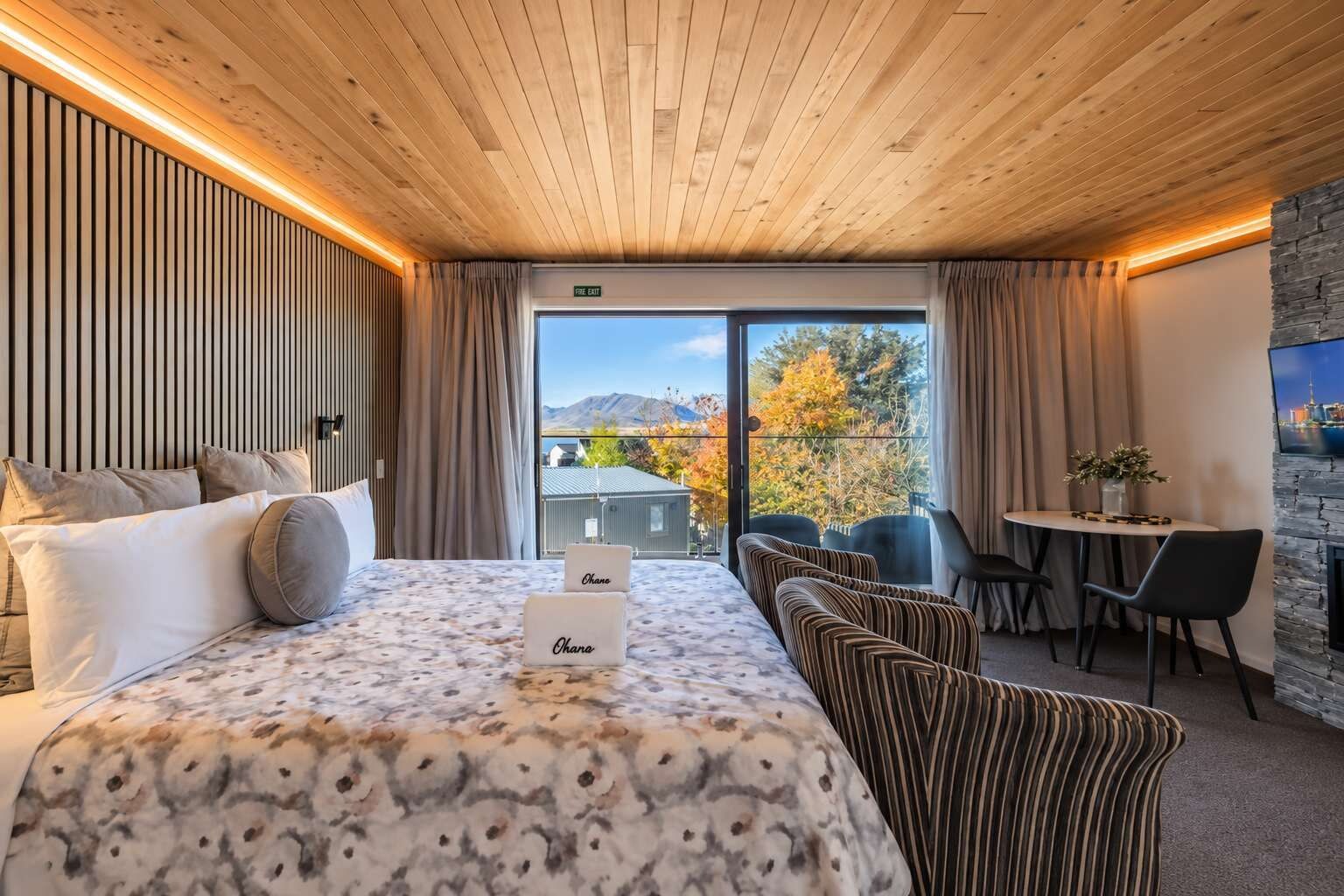 A hotel room with a large bed, a dining area, and a view of the outdoors.
