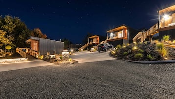 A modern building with a car parked in front, surrounded by a landscaped area with rocks and plants.