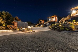 A modern building with a car parked in front, surrounded by a landscaped area with rocks and plants. - Starry Retreat | Lake Views + Fireplace (Lake Tekapo)