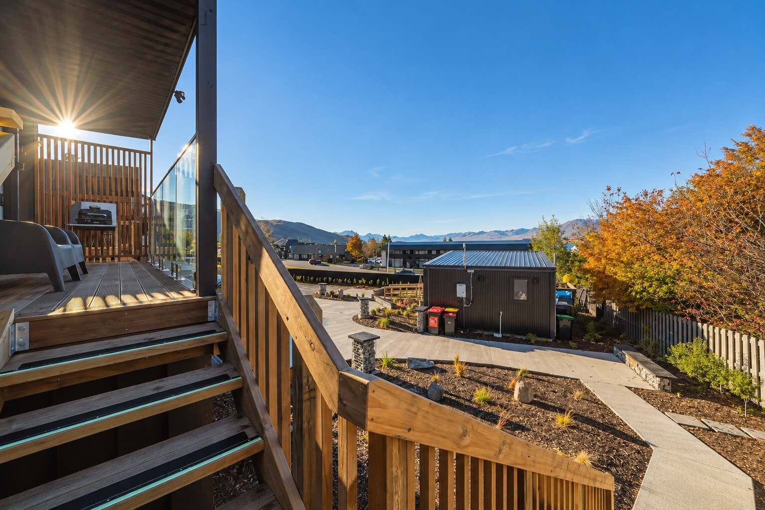 A wooden deck with a grill, a small shed, and a landscaped garden area.