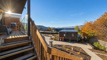 A wooden deck with a grill, a small shed, and a landscaped garden area.