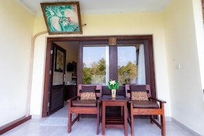 A wooden table with four chairs, a vase with flowers, and a door with a number sign. - Room-deluxe Double or Twin With Pool vie (Ubud)