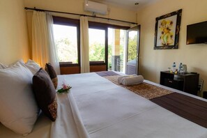 A hotel room with a large bed, a small desk, a television, and a window with curtains. - Room-deluxe Double or Twin With Pool vie (Ubud)