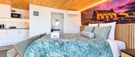 A modern bedroom with a bed, bedside table, and a view of a building through a window.