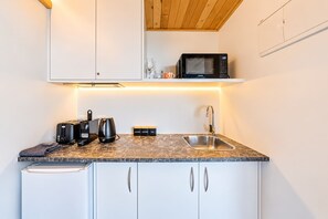 A compact kitchen with a microwave, toaster, coffee maker, and a sink. - Starlight Escape | Lake Views + Balcony (Lake Tekapo)