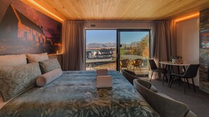 Une chambre d’hôtel avec un lit, un coin repas et une vue sur les montagnes.