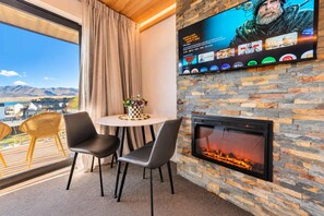 Une pièce avec une cheminée, un téléviseur fixé au mur et une table avec des chaises.