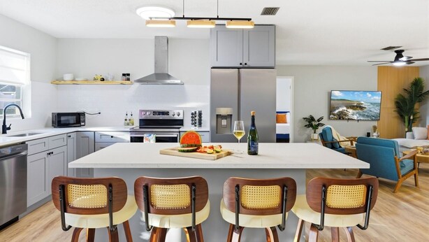 A modern kitchen with a central island, built-in appliances, and a dining area with four chairs. - Heated Pool • Games • Fire Pit • BBQ • Sleeps 12 (Bradenton)