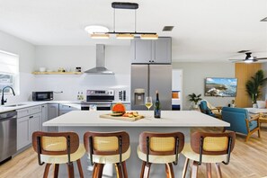 Een moderne keuken met een centraal eiland, inbouwapparatuur en een eethoek met vier stoelen.