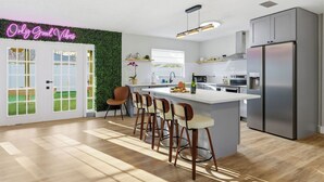 A modern kitchen with a central island, bar stools, a stainless steel refrigerator, and a neon sign on the wall. - Heated Pool • Games • Fire Pit • BBQ • Sleeps 12 (Bradenton)