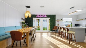A modern kitchen with a wooden island, bar stools, and a neon sign. - Heated Pool • Games • Fire Pit • BBQ • Sleeps 12 (Bradenton)