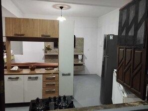 Una cocina compacta con armarios de madera, estufa integrada y una lámpara colgante.