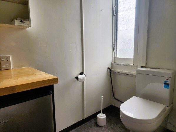 Une petite salle de bain propre, équipée de toilettes, d’un lavabo et d’une fenêtre.