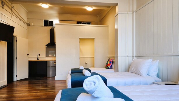 Une chambre d’hôtel avec deux lits, une kitchenette et une salle de bain.