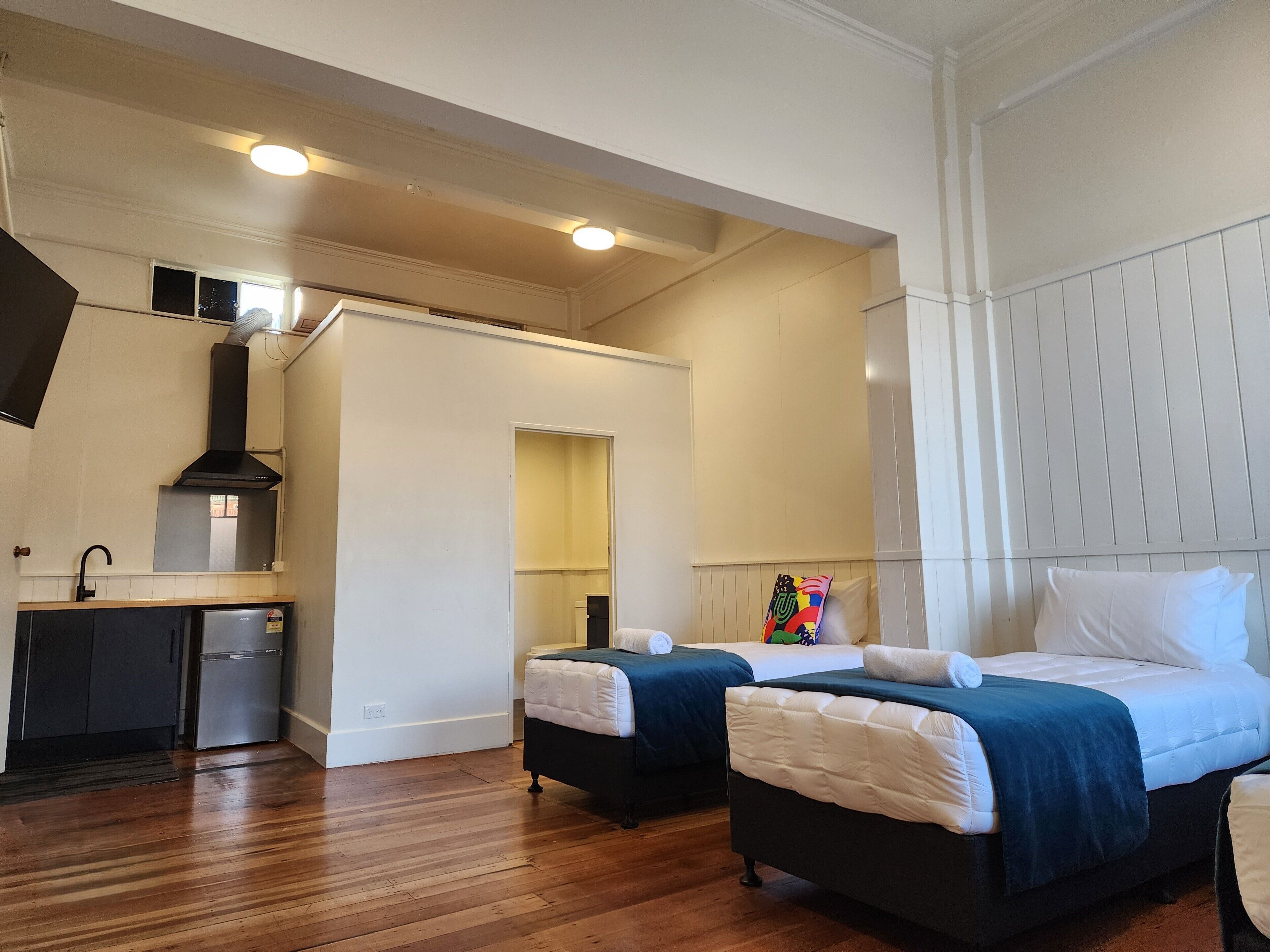 Habitación de hotel con dos camas, kitchenette y baño.