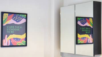 A wall with two framed posters and a mirrored cabinet.