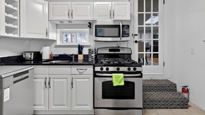 A kitchen with white cabinets, a microwave, a stove, and a toaster. - Cozy&Spacious 7Br home in Malden + free Parking (Malden)