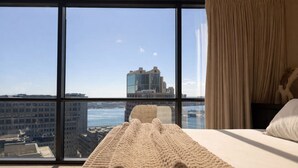 Un cuarto de hotel con un ventanal grande, una cama y vistas a la ciudad.
