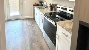Une cuisine avec des meubles blancs, un four à micro-ondes, une cuisinière et un lave-vaisselle.