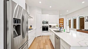Une cuisine moderne dotée d’appareils électroménagers en acier inoxydable, de meubles blancs et d’un plan de travail en marbre.