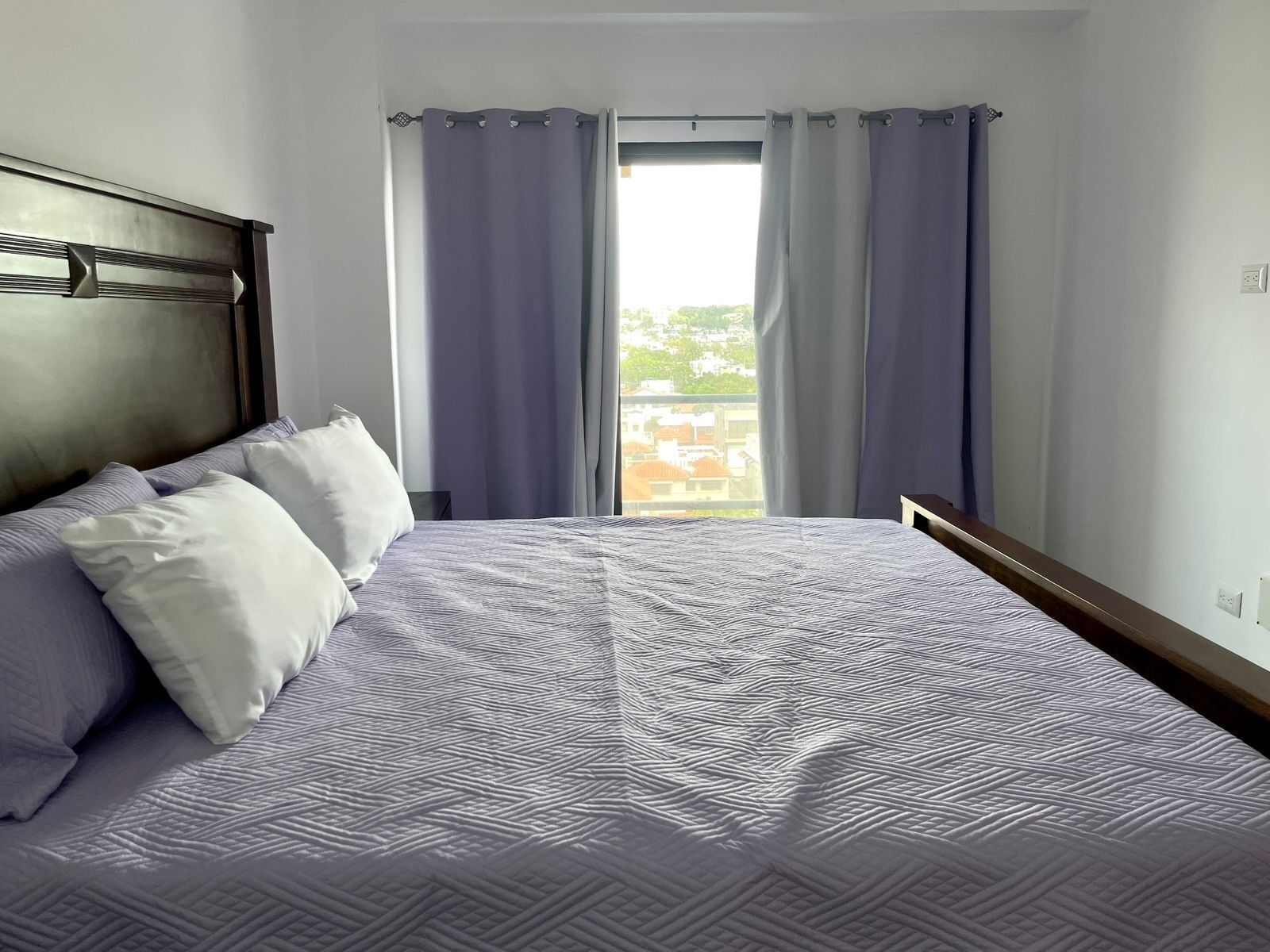 A neatly made bed with a patterned bedspread, a headboard, and two pillows.