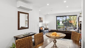 Una sala de estar moderna con comedor, un espejo grande y vistas al exterior.