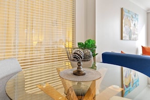 Un salon moderne avec une table en verre, un bol décoratif en métal, une plante en pot et un canapé bleu.